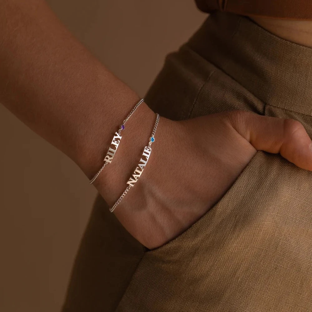 Duas pulseiras com nome prata e pedra de nascimento no pulso