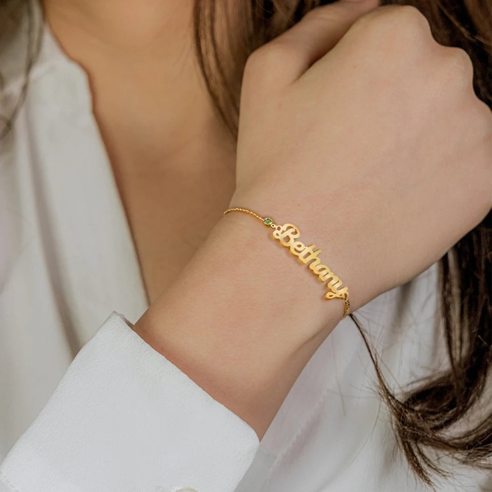 Pulseira com nome Bethany em letra cursiva dourada no pulso