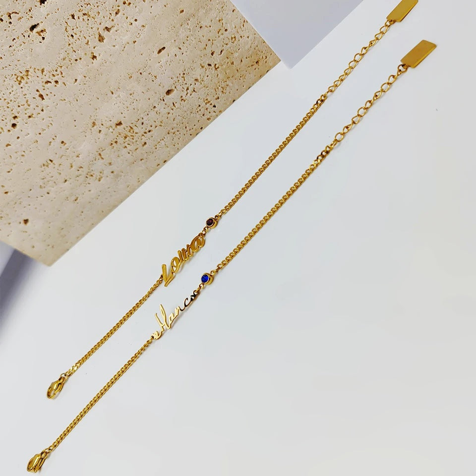 Pulseiras groumet douradas com nome e pedra do mês esticadas