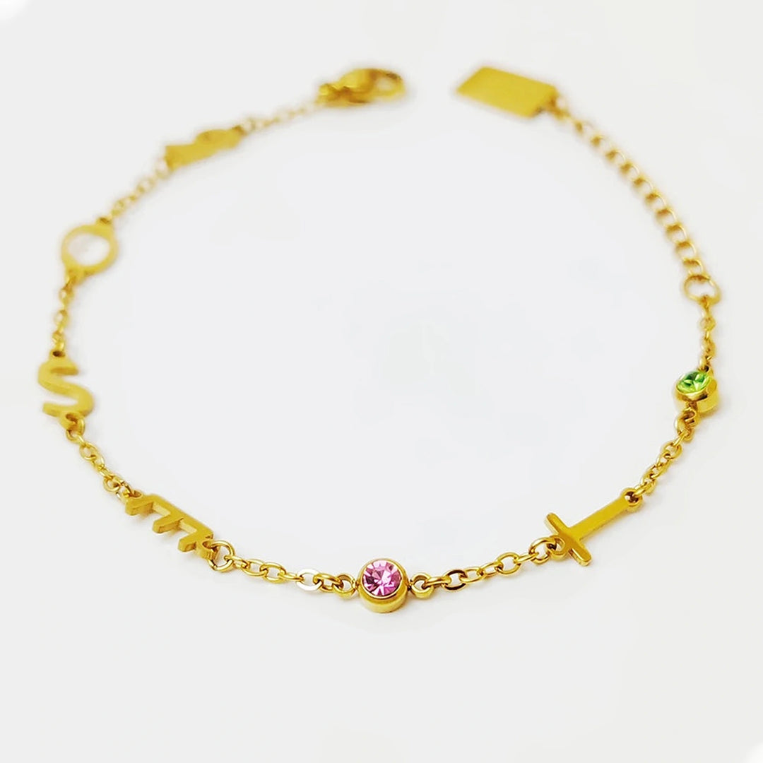 Pulseira com iniciais douradas e pedras do mês rosa e verde sobre fundo branco
