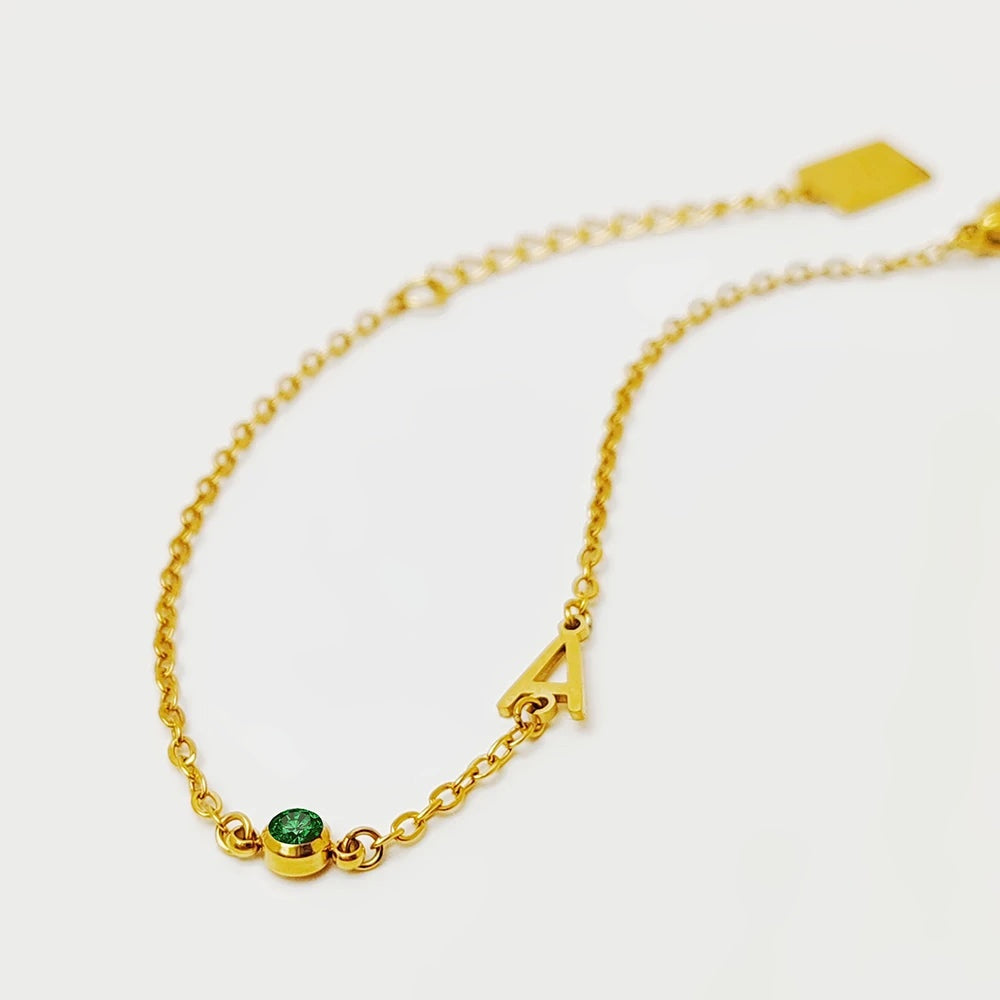 Pulseira com inicial A e pedra verde do mês dourada
