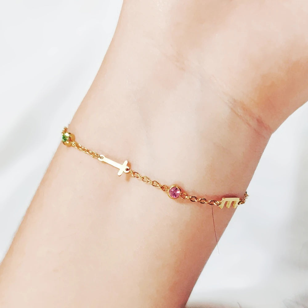 Pulseira com inicial e pedras coloridas no pulso