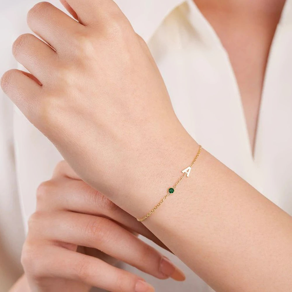 Pulseira delicada com inicial A e pedra verde no pulso
