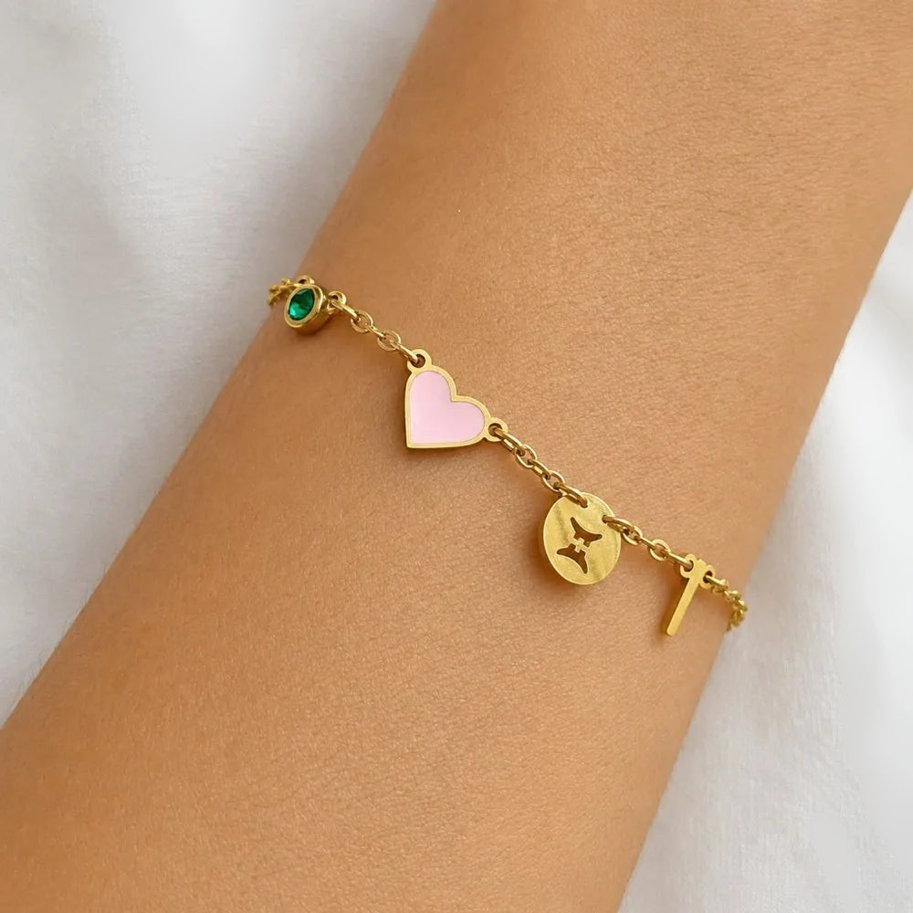 Pulseira com coração rosa, signo e inicial T usada no pulso