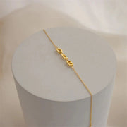 Pulseira personalizada com três letras laterais douradas sobre pedestal