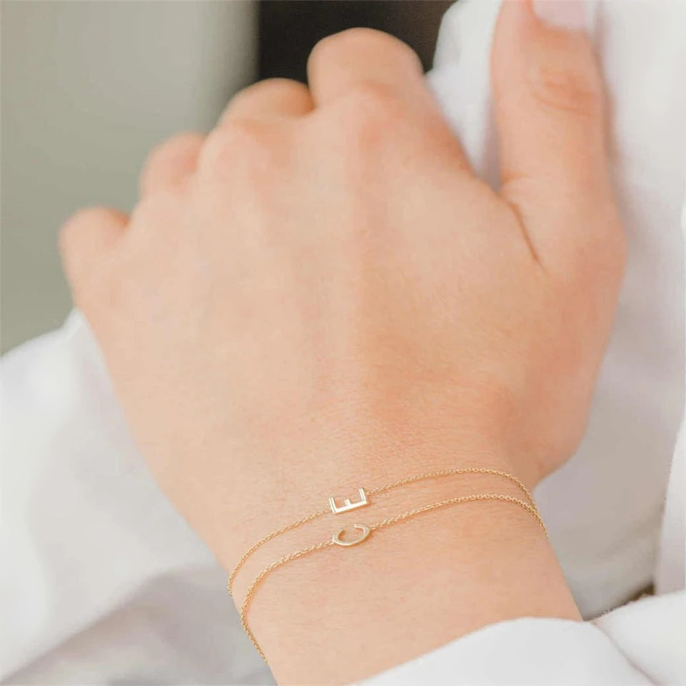 Pulseiras finas com inicial lateral usadas juntas