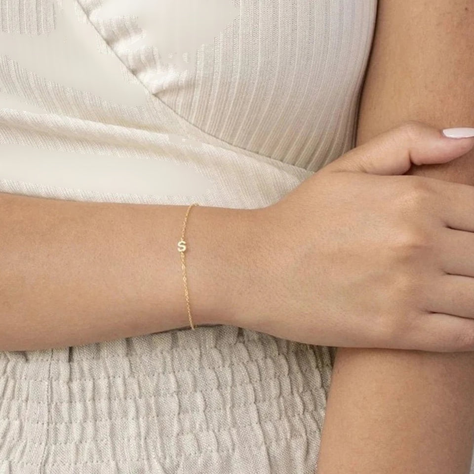 Pulseira delicada com uma letra lateral dourada no pulso
