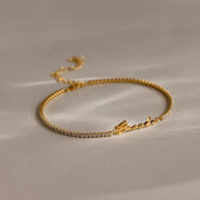 Pulseira riviera com nome em letra cursiva dourada e zircônias