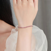 Pulseira riviera de moissanite vermelho-alaranjada no pulso